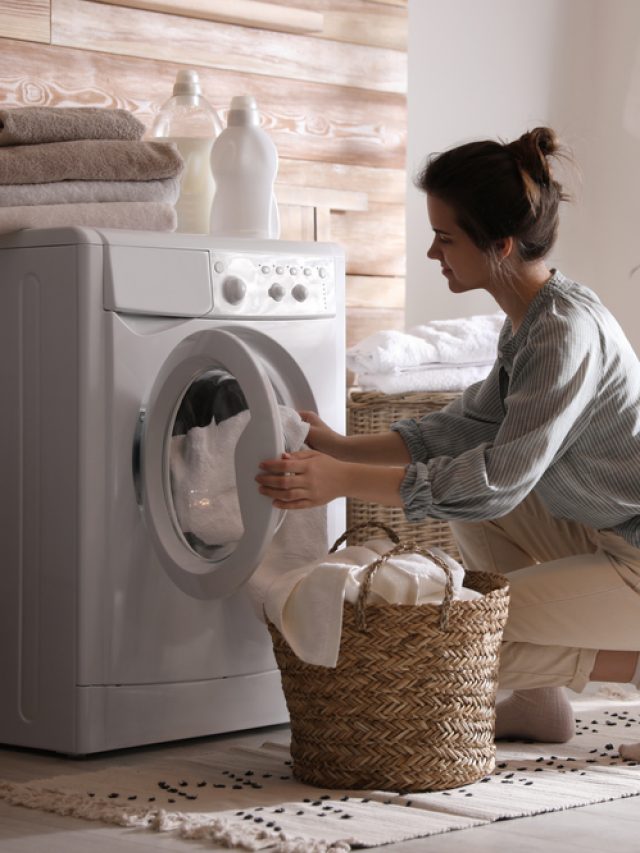 Young,Woman,Taking,Laundry,Out,Of,Washing,Machine,At,Home